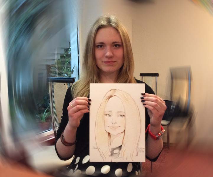 Девушка держит свой шарж в кафе Оранжерея